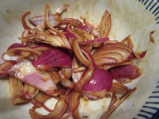 Die roten Zwiebeln werden in Olivenöl-Balsamico-Dressing einlegt.